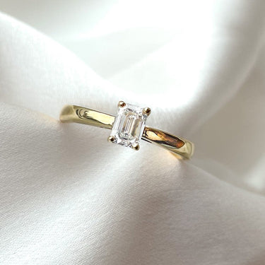 Emerald solitaire verlovingsring van 18 karaat geelgoud met 0.30 ct lab-grown diamant getoond in suede